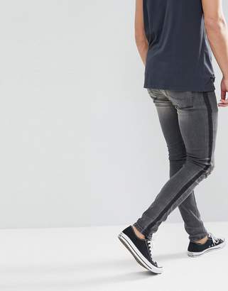 ASOS DESIGN super skinny jeans in washed black with side stripe and knee rips