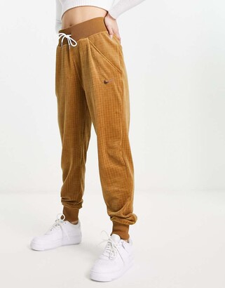 nike all over logo print joggers in camel