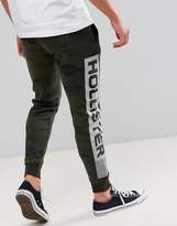 Thumbnail for your product : Hollister print logo camo print skinny joggers in olive green