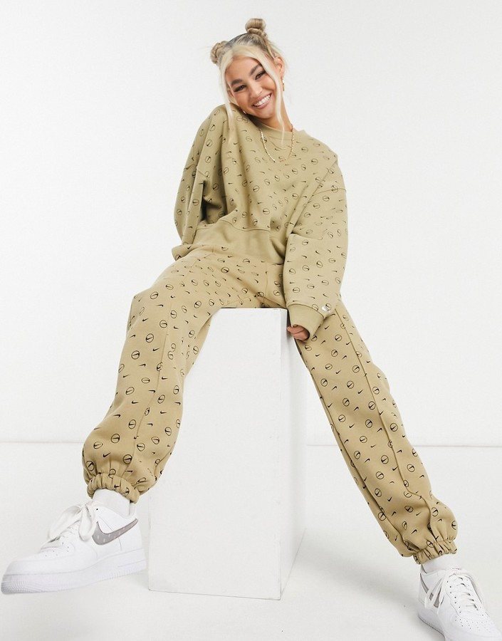 nike all over logo print joggers in camel