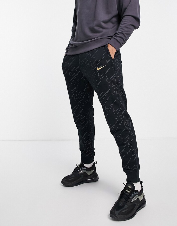 Nike all over swoosh print cuffed joggers in black and gold - ShopStyle  Trousers