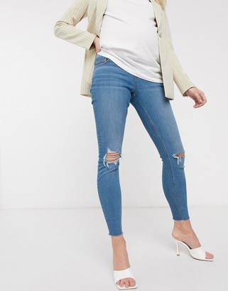 ASOS DESIGN Maternity high rise ridley 'skinny' jeans in lightwash blue with knee rips and raw hem with under bump