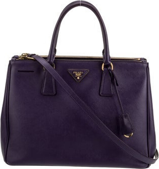 Prada Tote Purple Saffiano Lux Leather Gold-Tone Hardware Rolled Handles & Single Adjustable Shoulder Strap Dual Exterior Pockets Logo Jacquard Lining & Four Interior Pockets Open Top Protective Feet at Base Includes Dust Bag & Authenticity Card